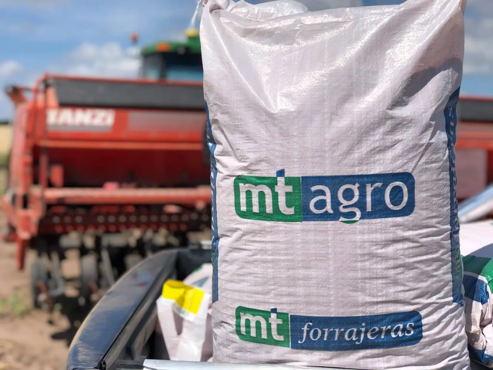 Bolsas de semillas forrajeras MT AGRO junto a una sembradora